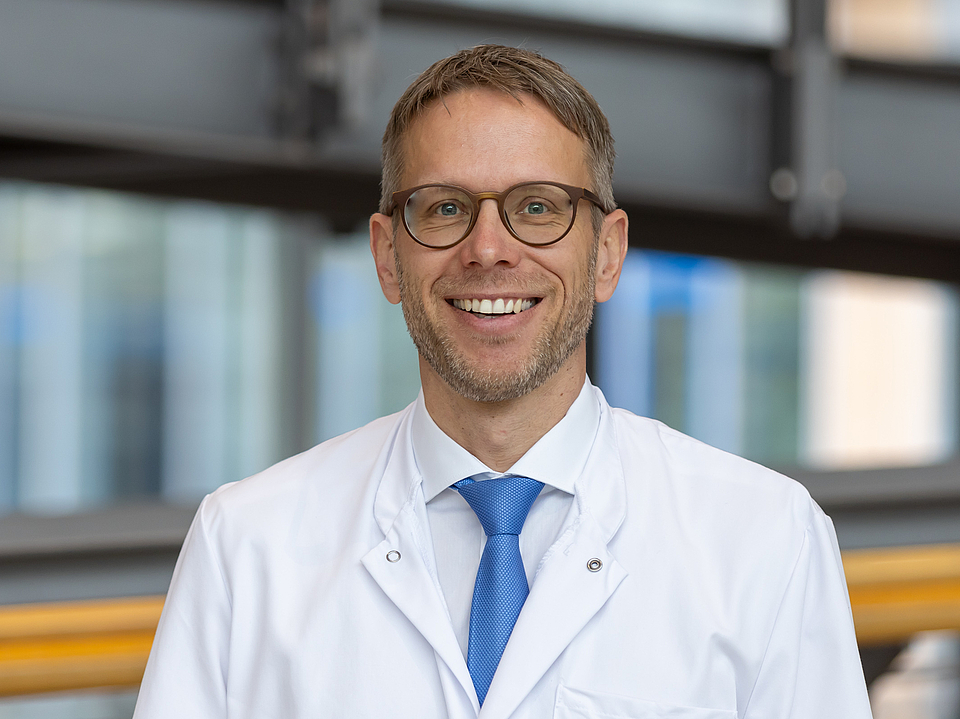 Arzt lächelt in die Kamera.