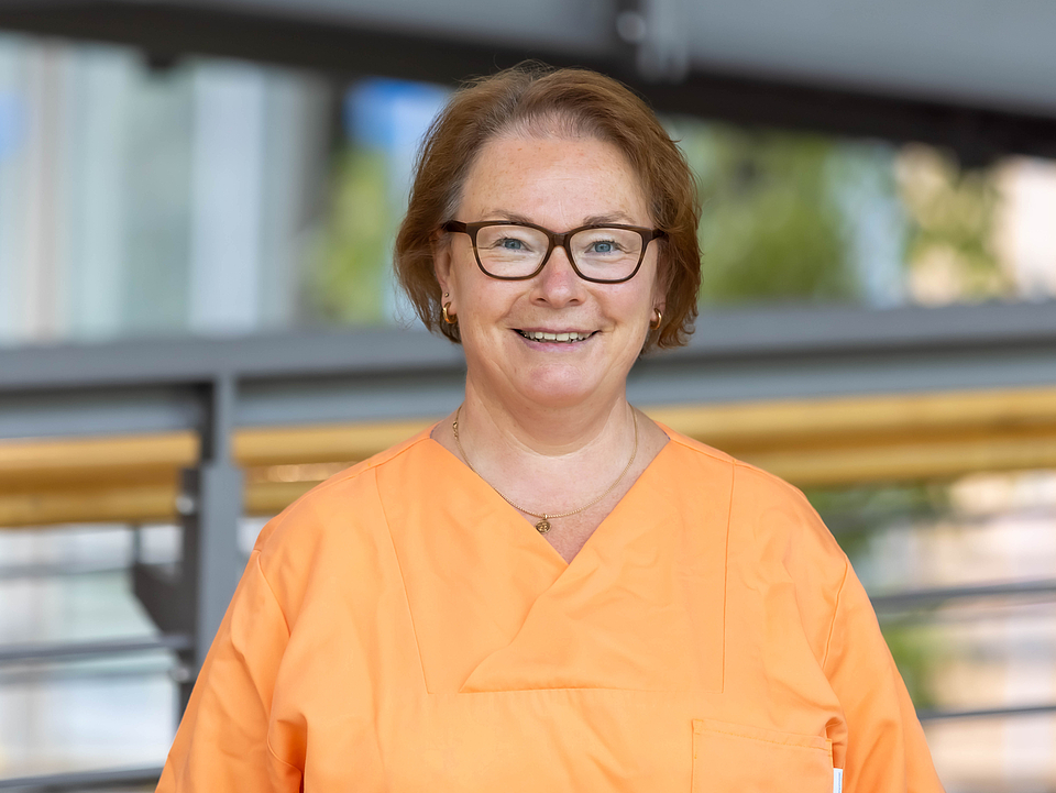 Pflegerin lächelt in die Kamera.