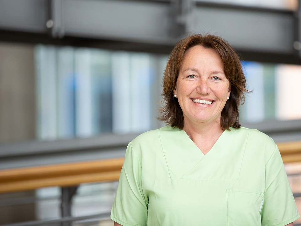 Pflegerin lächelt in die Kamera.