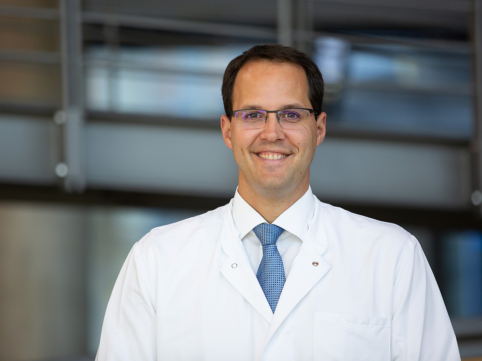 Ein Arzt lächelt in die Kamera.