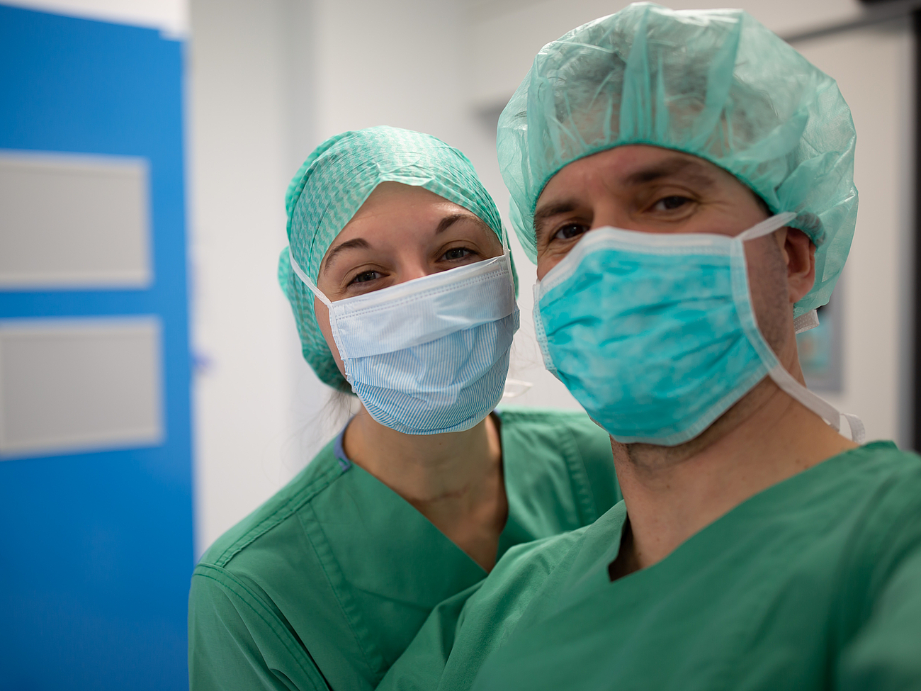 Zwei Ärzte machen ein Selfie mit Maske und OP-Haube.