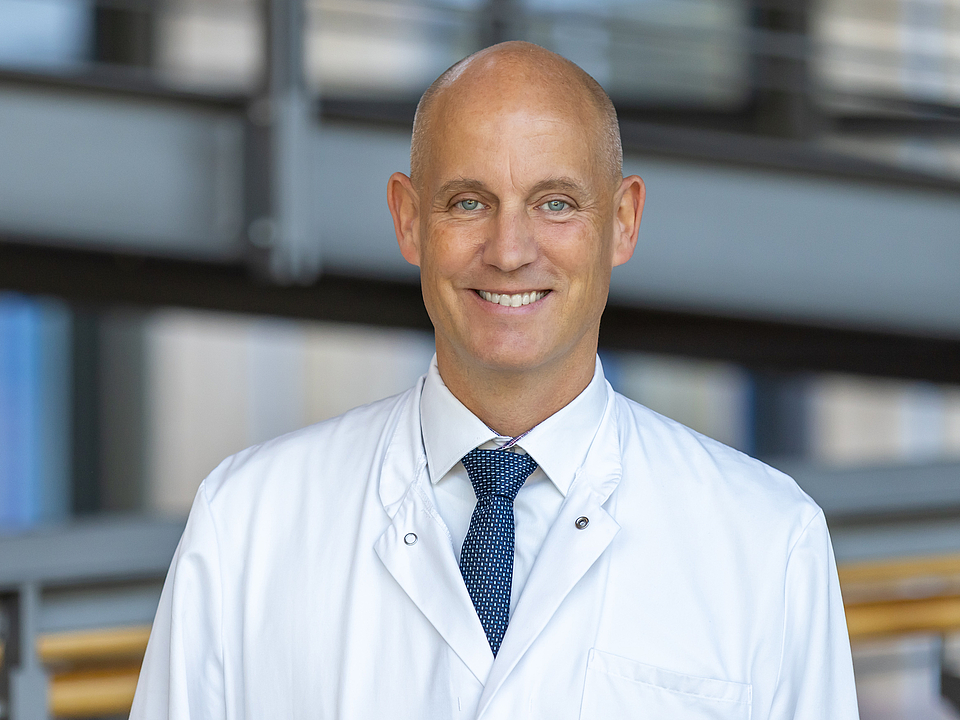 Arzt lächelt in die Kamera.