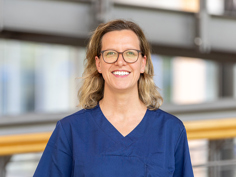 Pflegerin lächelt in die Kamera.