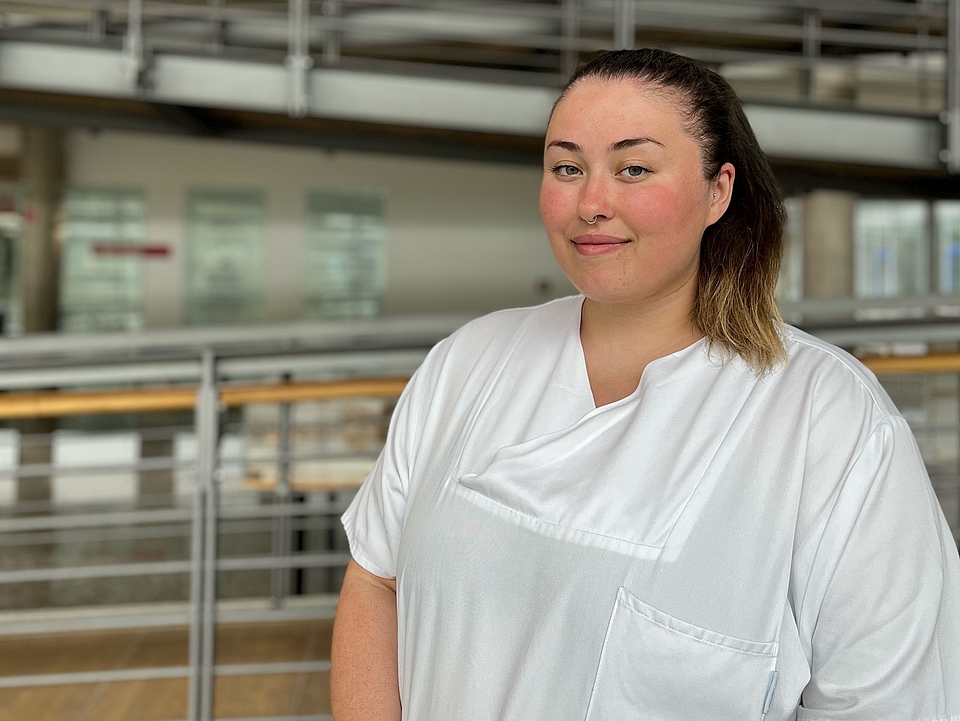 Pflegerin lächelt in die Kamera.