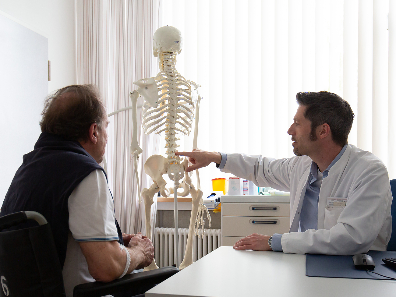 Patient und Arzt betrachten Skelett-Modell