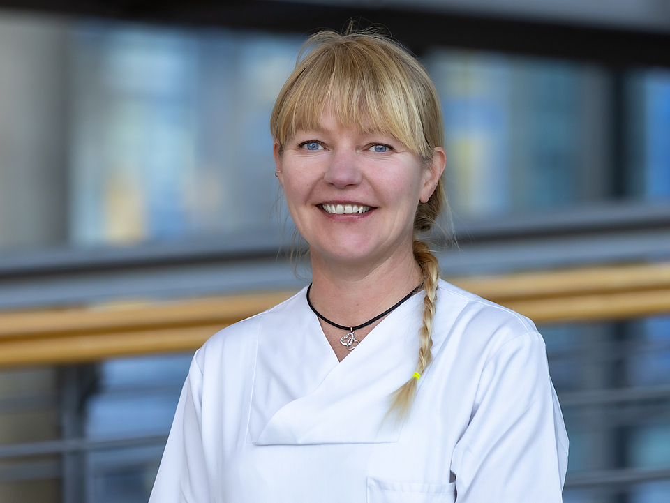 Pflegerin lächelt in die Kamera.