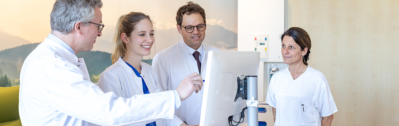 Ärzte unterhalten sich vor einem Computer im Stehen miteinander.