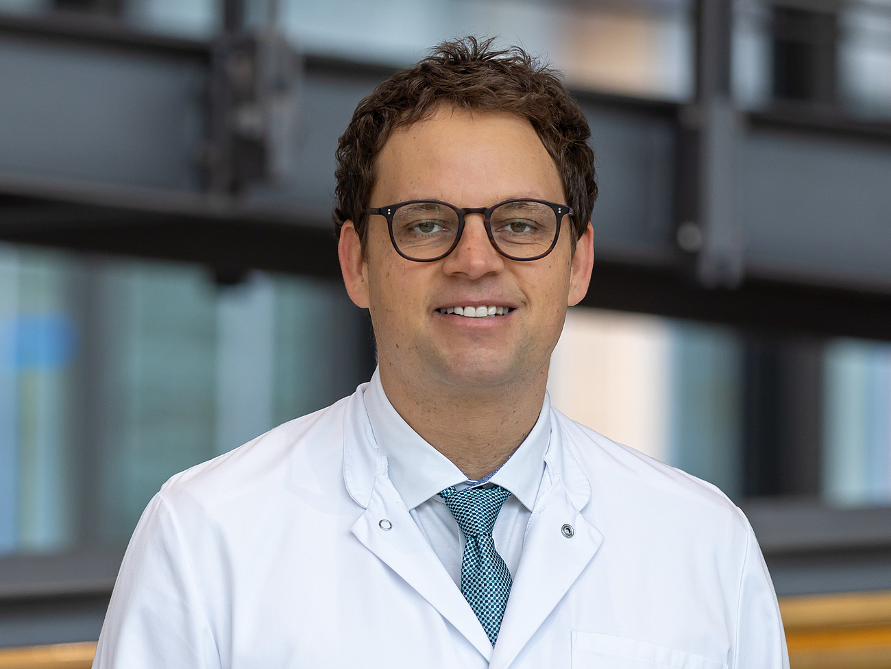 Arzt lächelt in die Kamera.