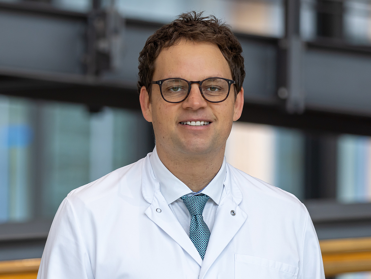 Arzt lächelt in die Kamera.