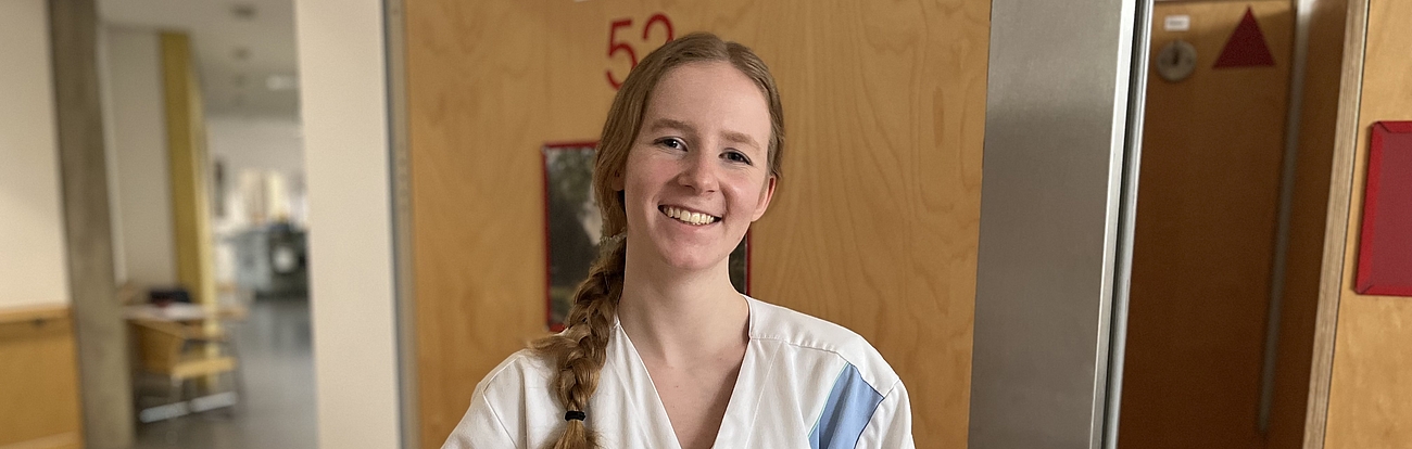 Eine Pflegerin hält ein Tablett mit dem Frühstück nach oben.