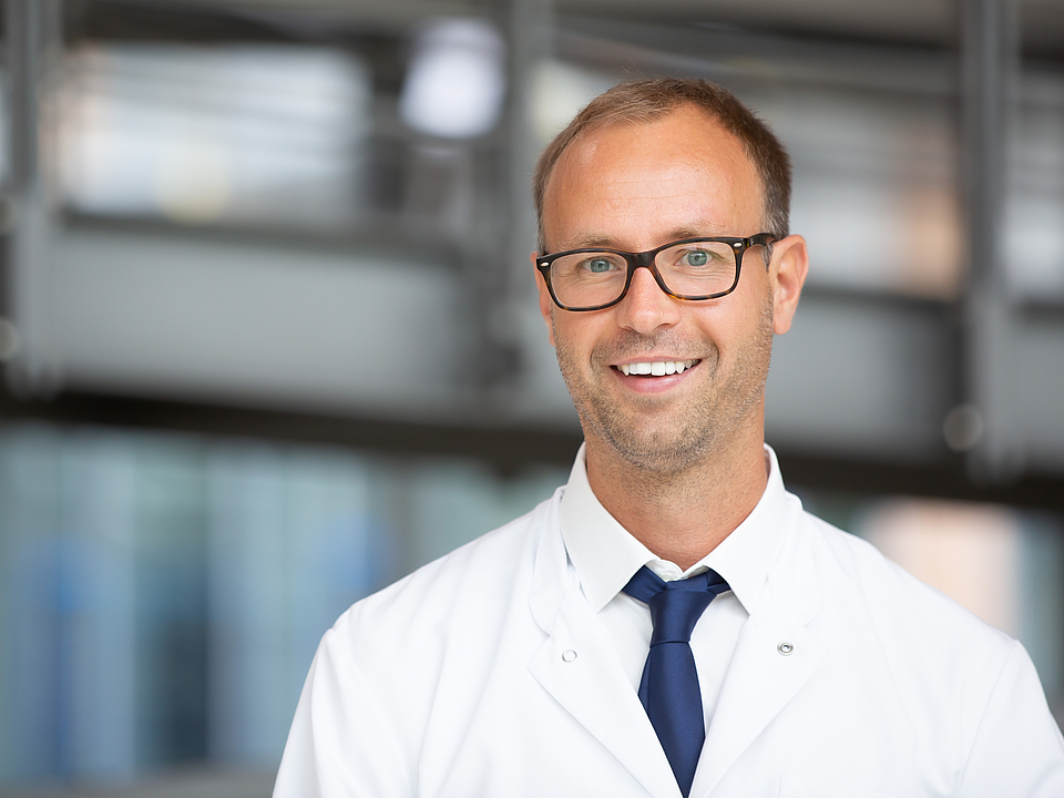 Ein Arzt lächelt in die Kamera.