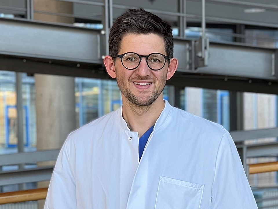 Arzt lächelt in die Kamera.