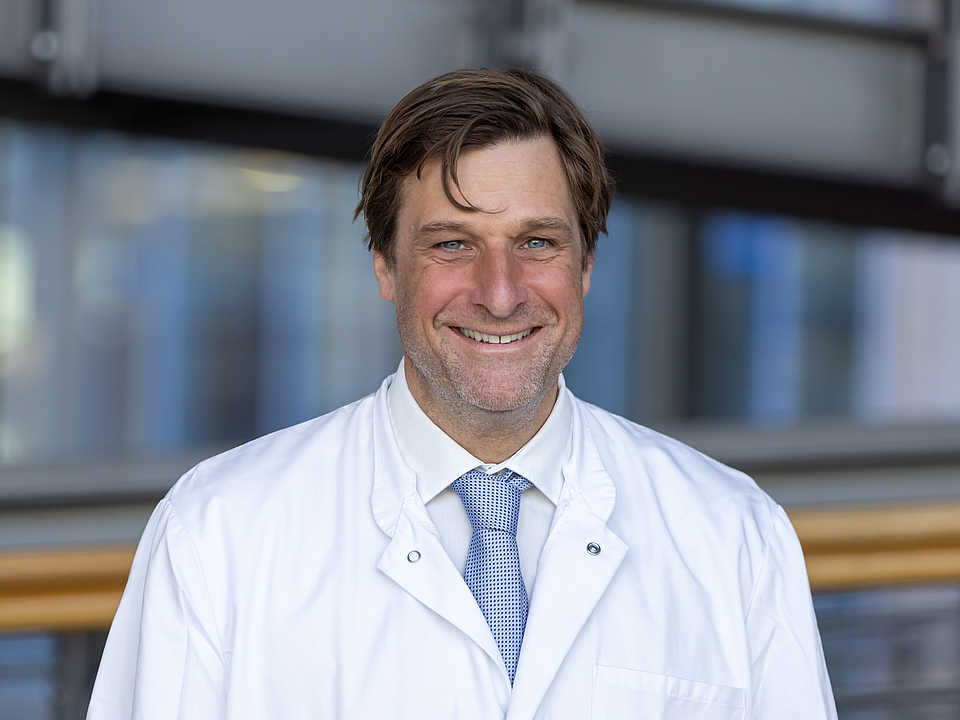 Arzt lächelt in die Kamera.