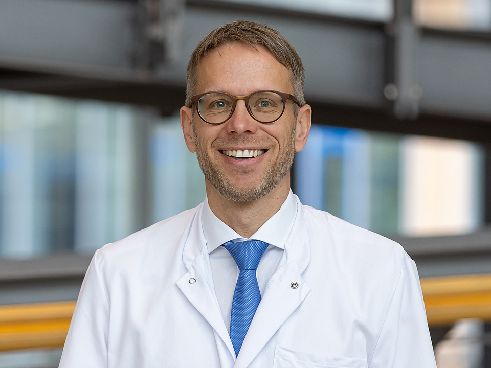 Arzt lächelt in die Kamera.