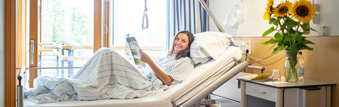 Patientin mit Zeitschrift im Krankenbett