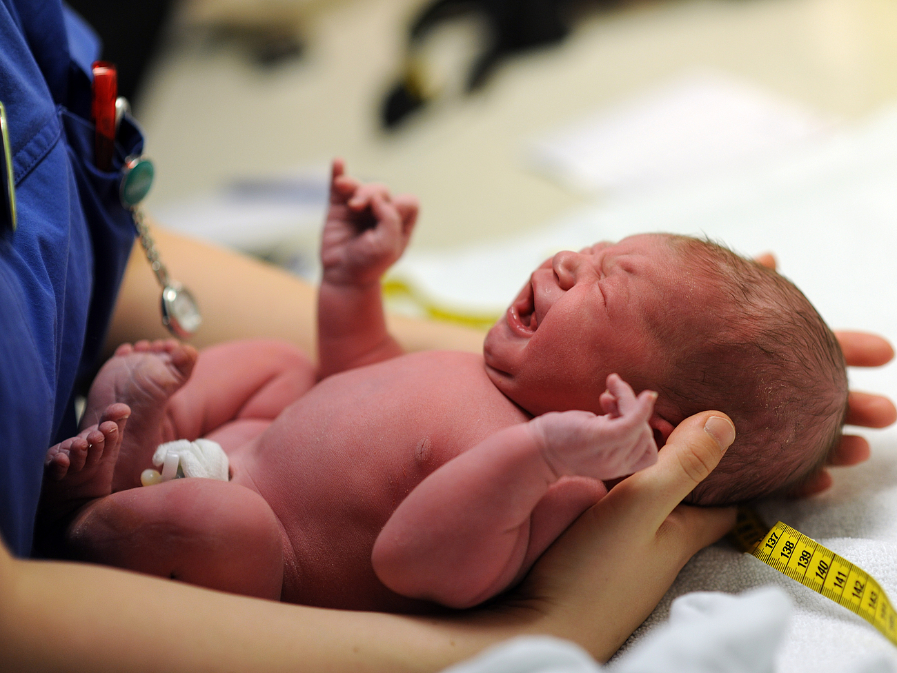 Baby nach der Geburt in den Händen einer medizinischen Fachkraft.