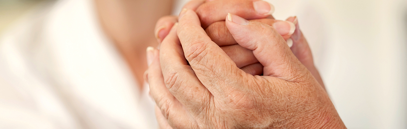 Ärztin hält altem Menschen die Hand