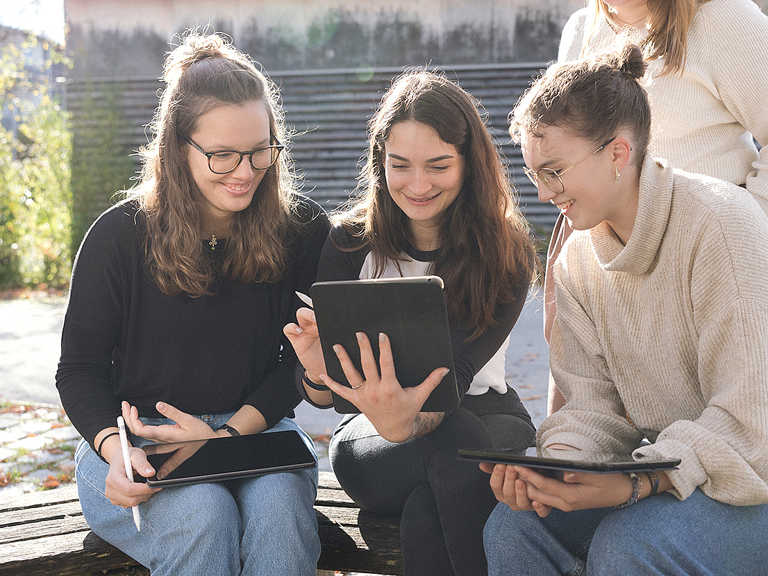 Schülerinnen der Berufsfachschule für Pflege Schülerinnen sitzen vor dem Schulgebäude