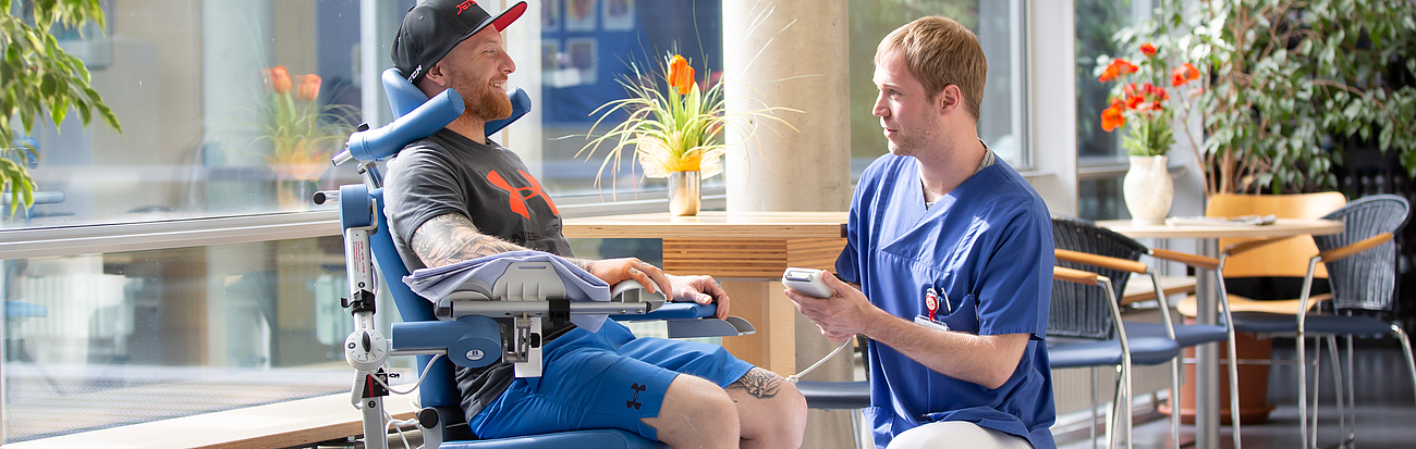 Ein Patient und ein Pfleger unterhalten sich im Flur.