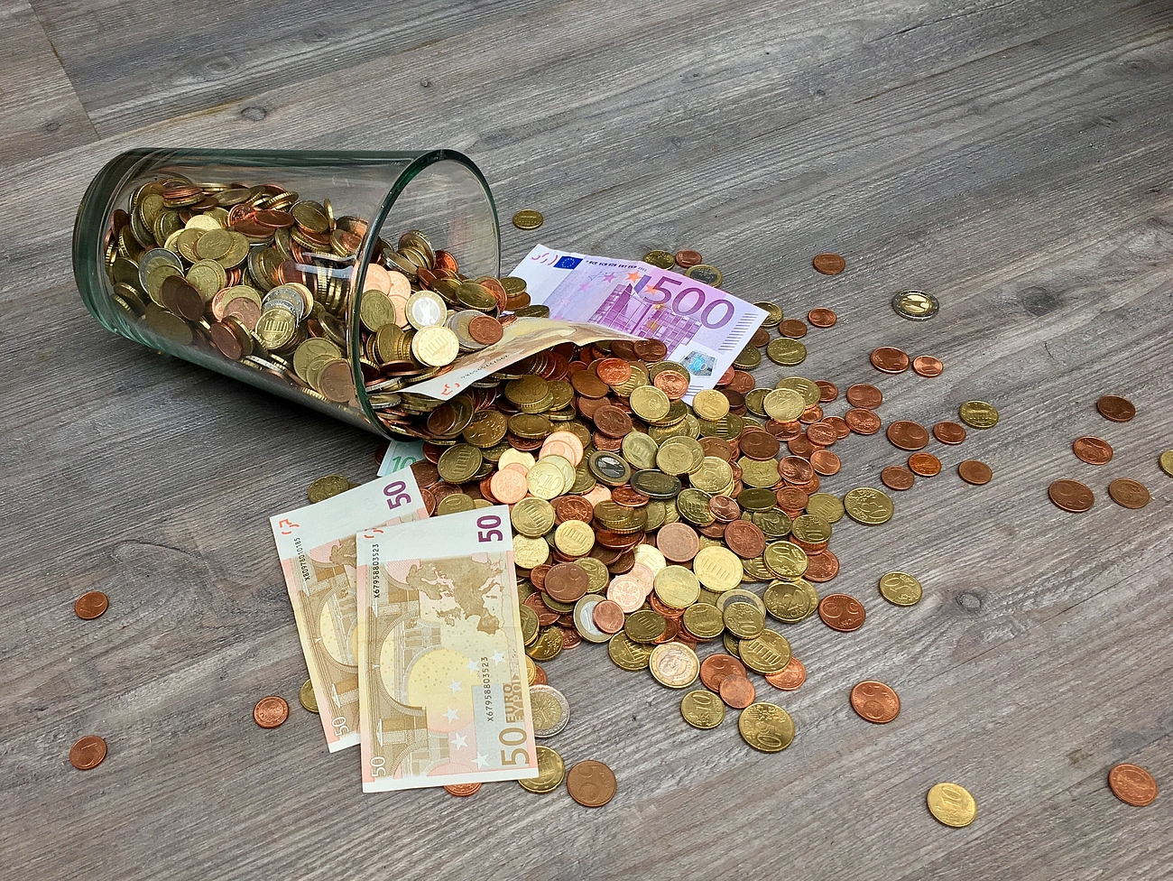 Eine umgeworfene Spardose aus der Geld fällt.