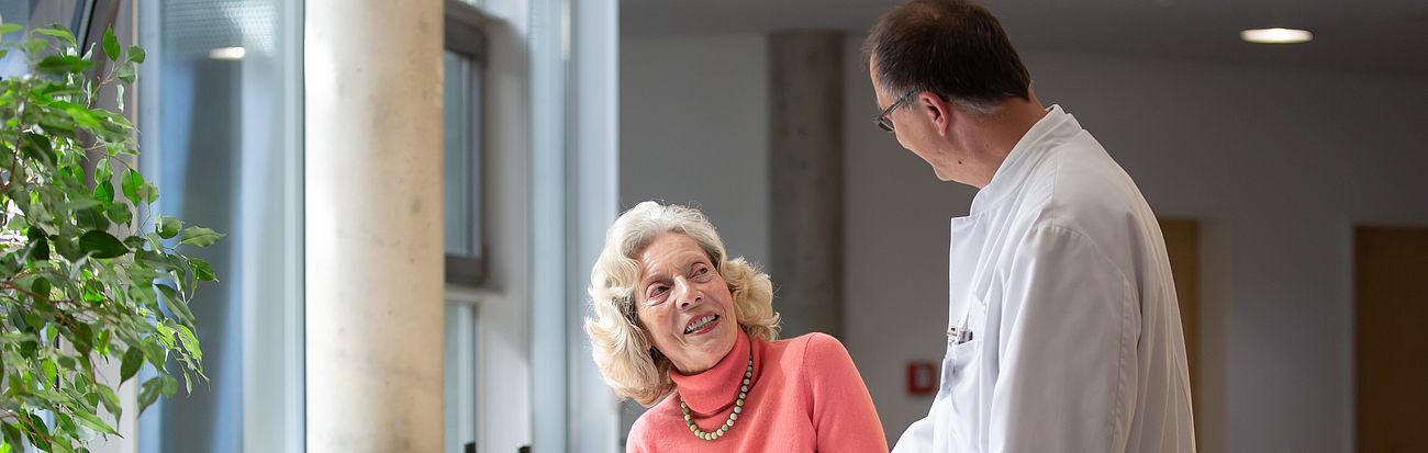 Ältere Patientin gemeinsam mit Dr. Lorenzl auf einer Station des Krankenhauses